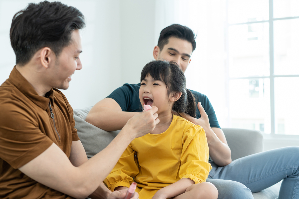 A father applying makeup to his young daughter.