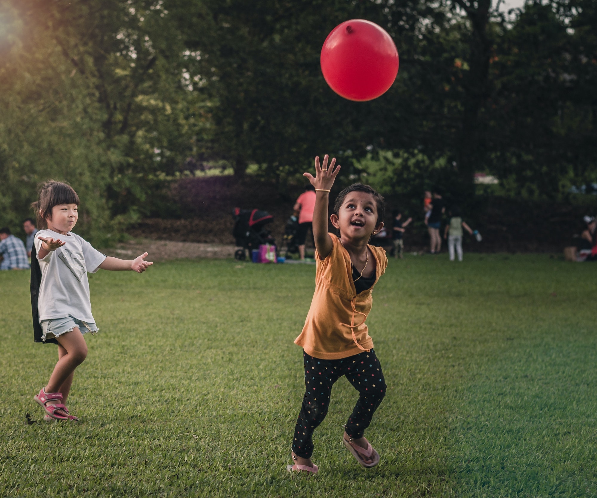 two children playing outside with a red balloon