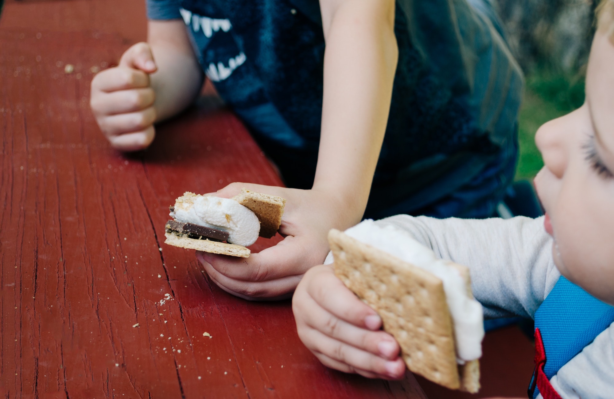 two kids eating s'mores at picnic table