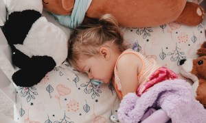Girl toddler with pacifier napping in crib.
