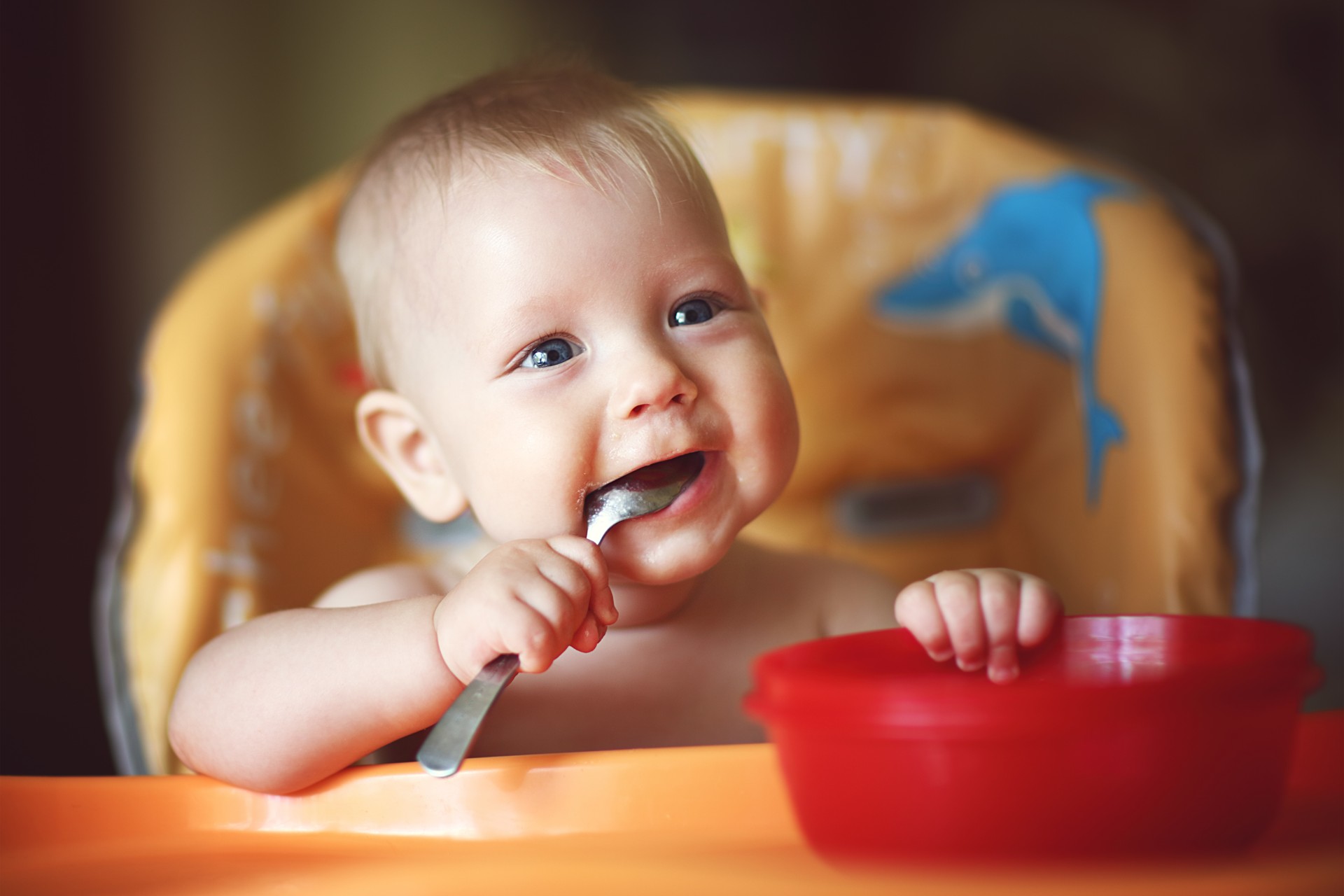 Happy toddler eating from red bowl