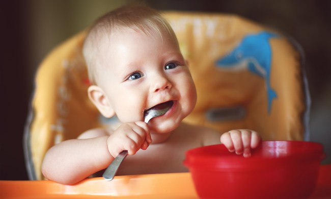 Happy baby eating from a red bowl