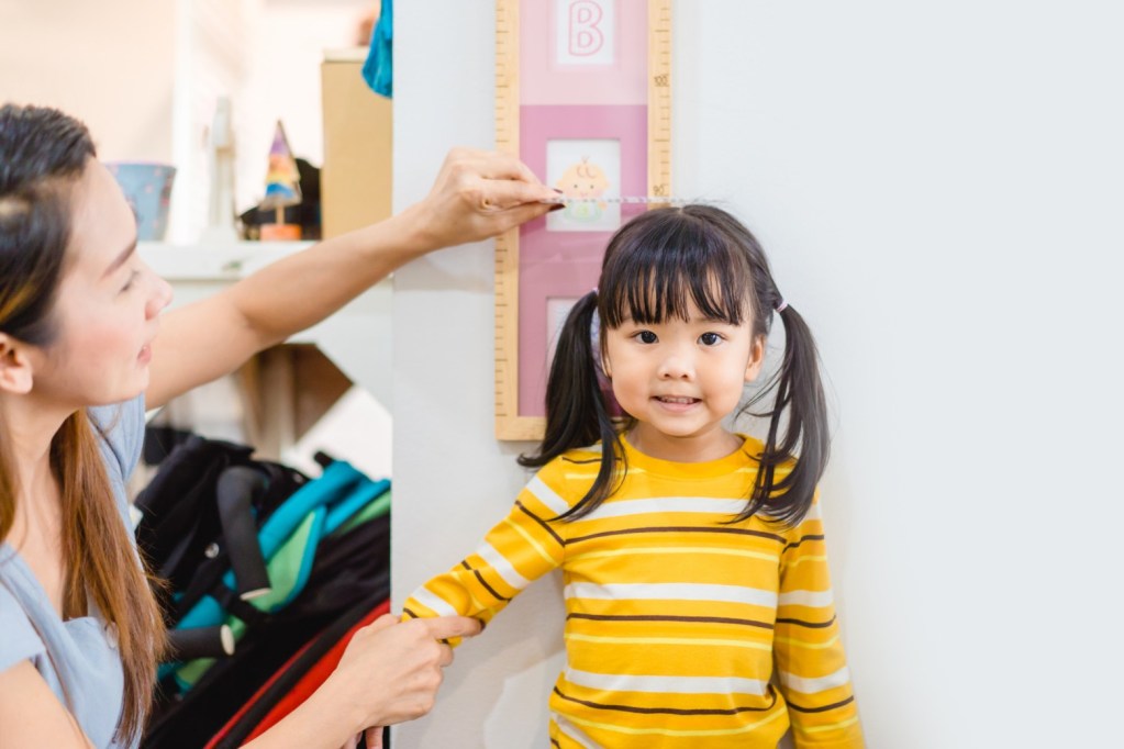 Mother measuring daughter's height against a wall.