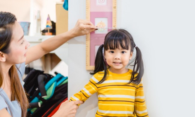 Mother measuring daughter's height against a wall.
