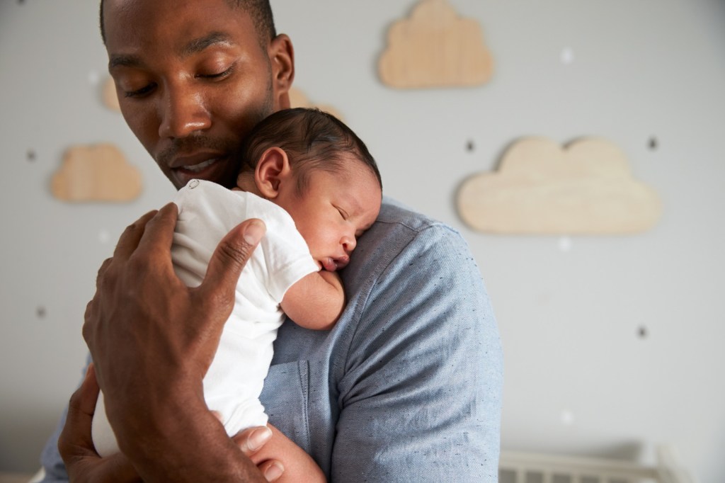 Father holding baby in nursery