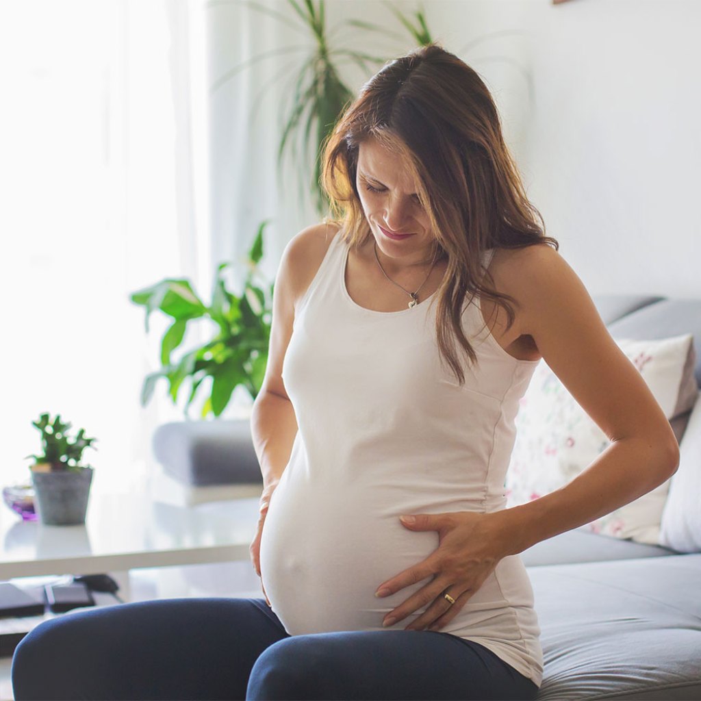 Pregnant woman on couch holding her stomach