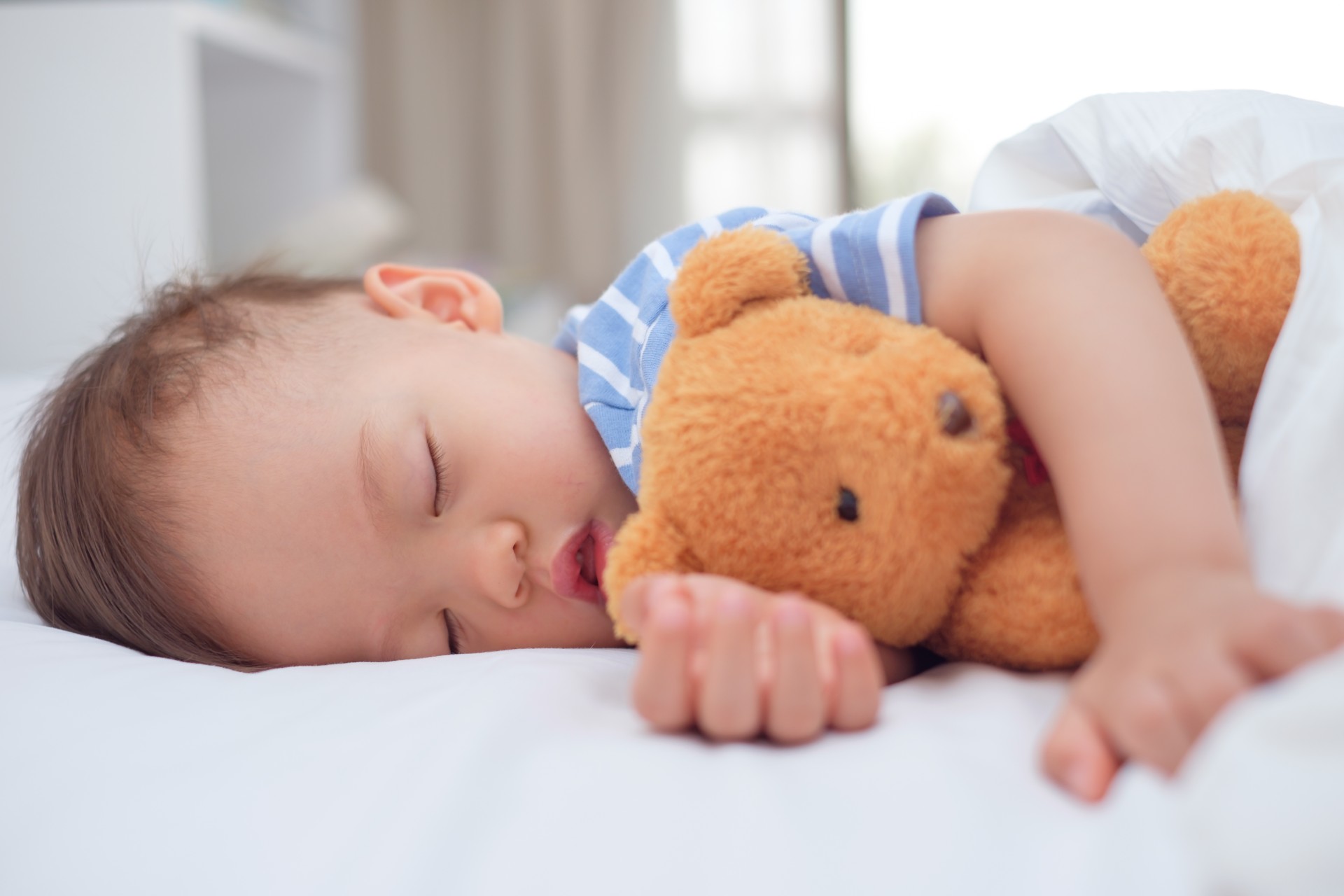 Toddler boy sleeping with Teddy bear