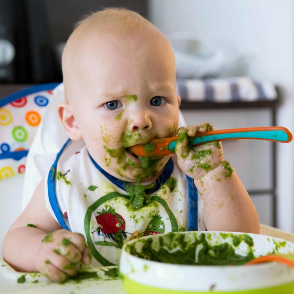 Baby making a mess while eating puree