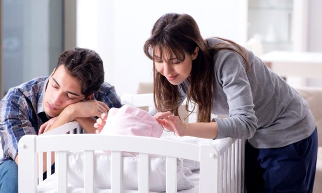 Parents at crib of their sleeping baby