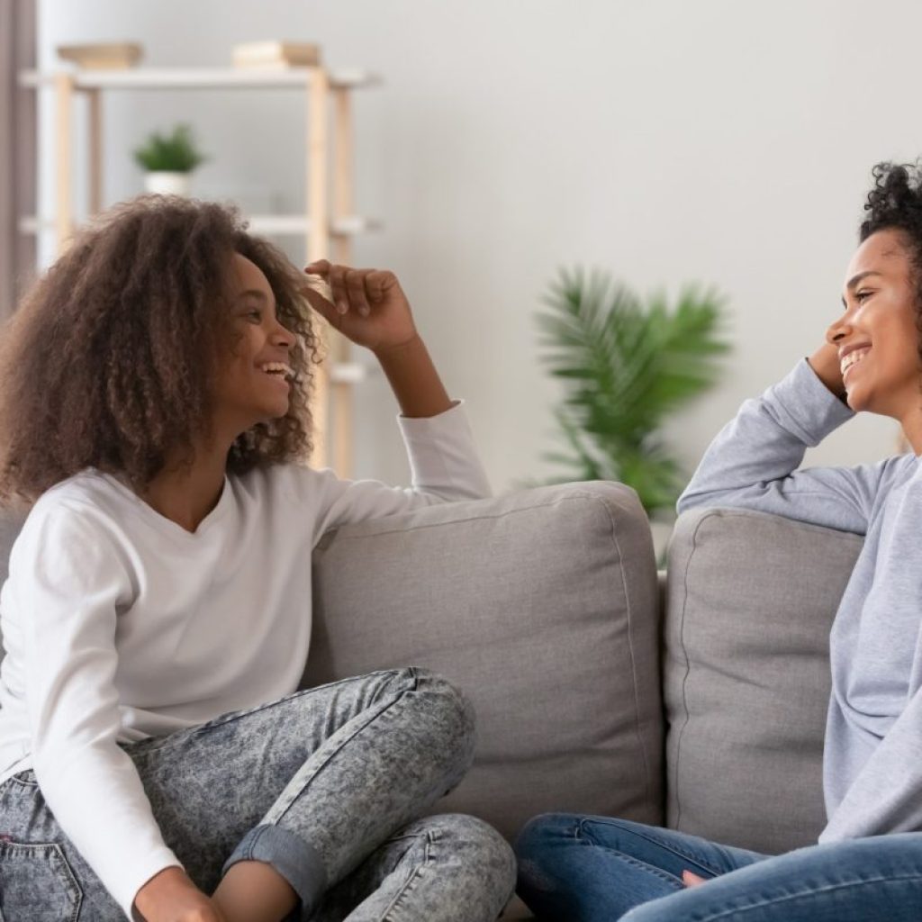 Mother and teenage daughter on couch talking