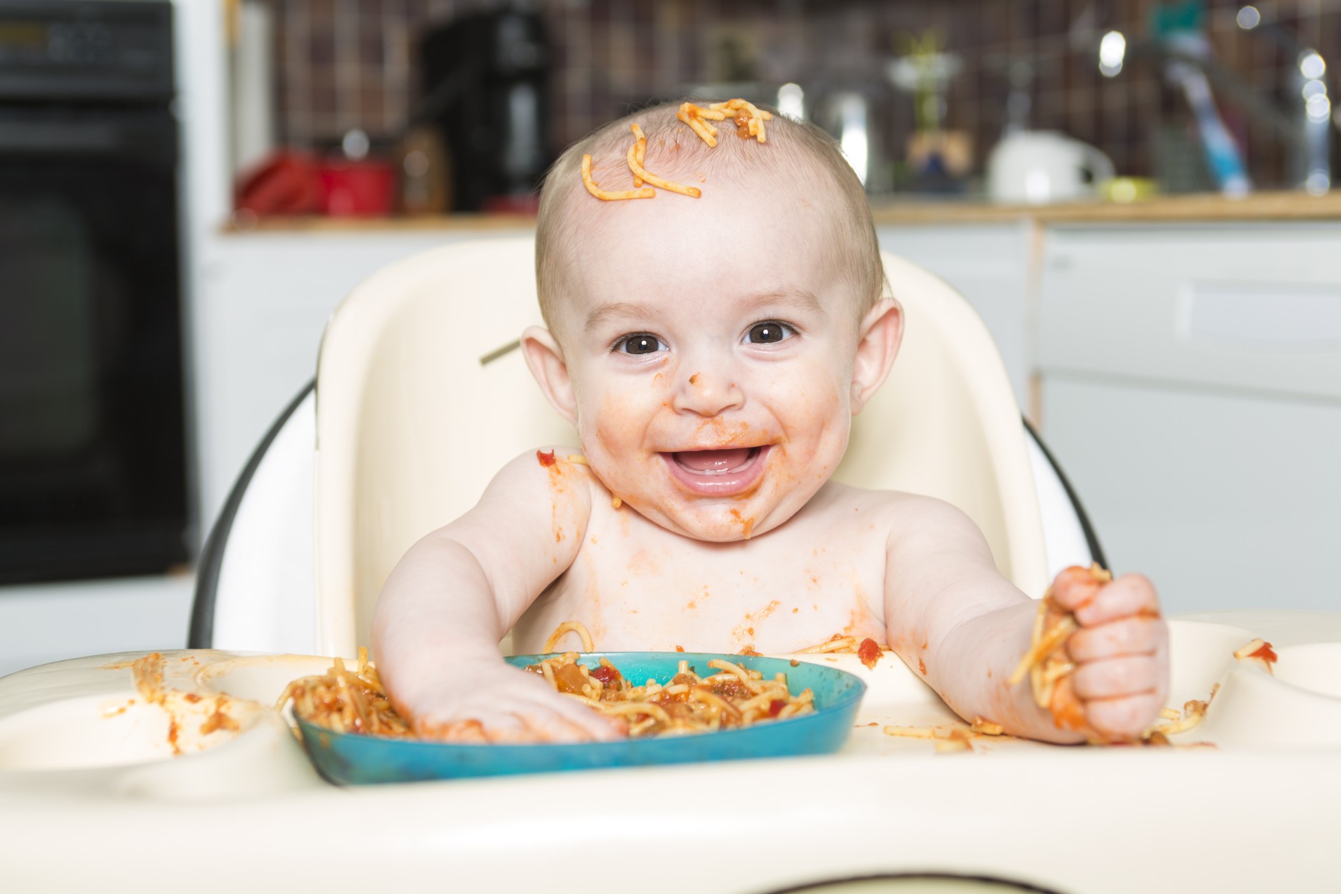 Smiling baby eating and making a mess