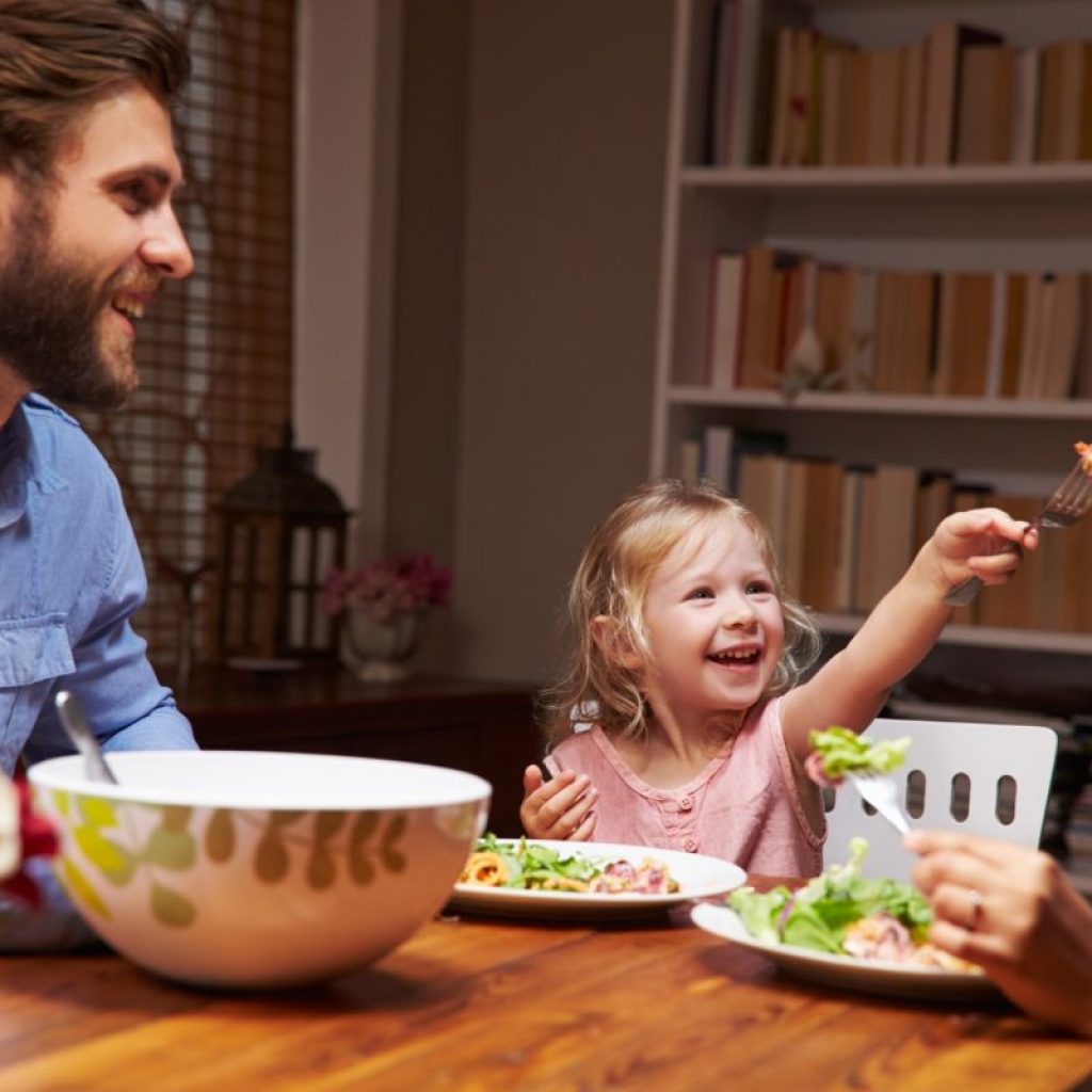 Family of three eating dinner at table at home