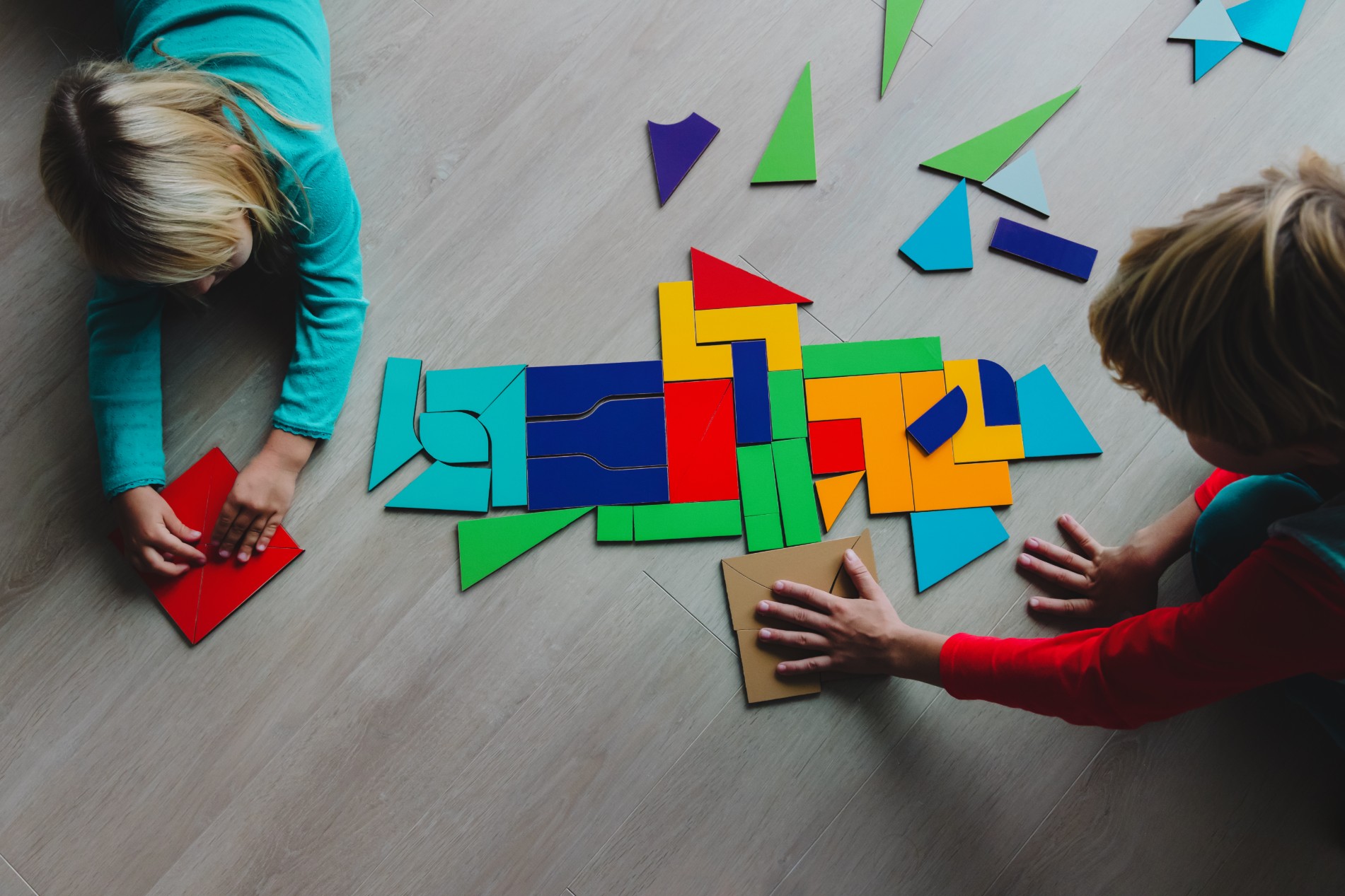 Two young kids playing with tangram puzzle