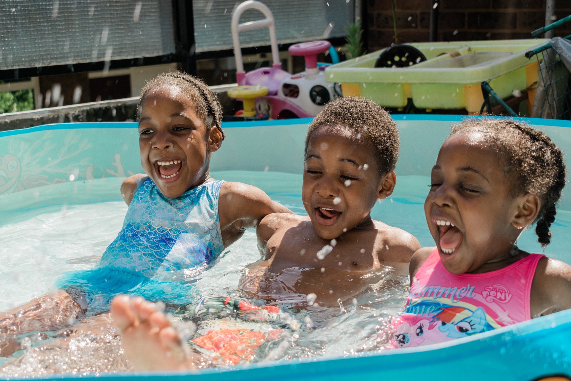 Three kids laughing in pool.