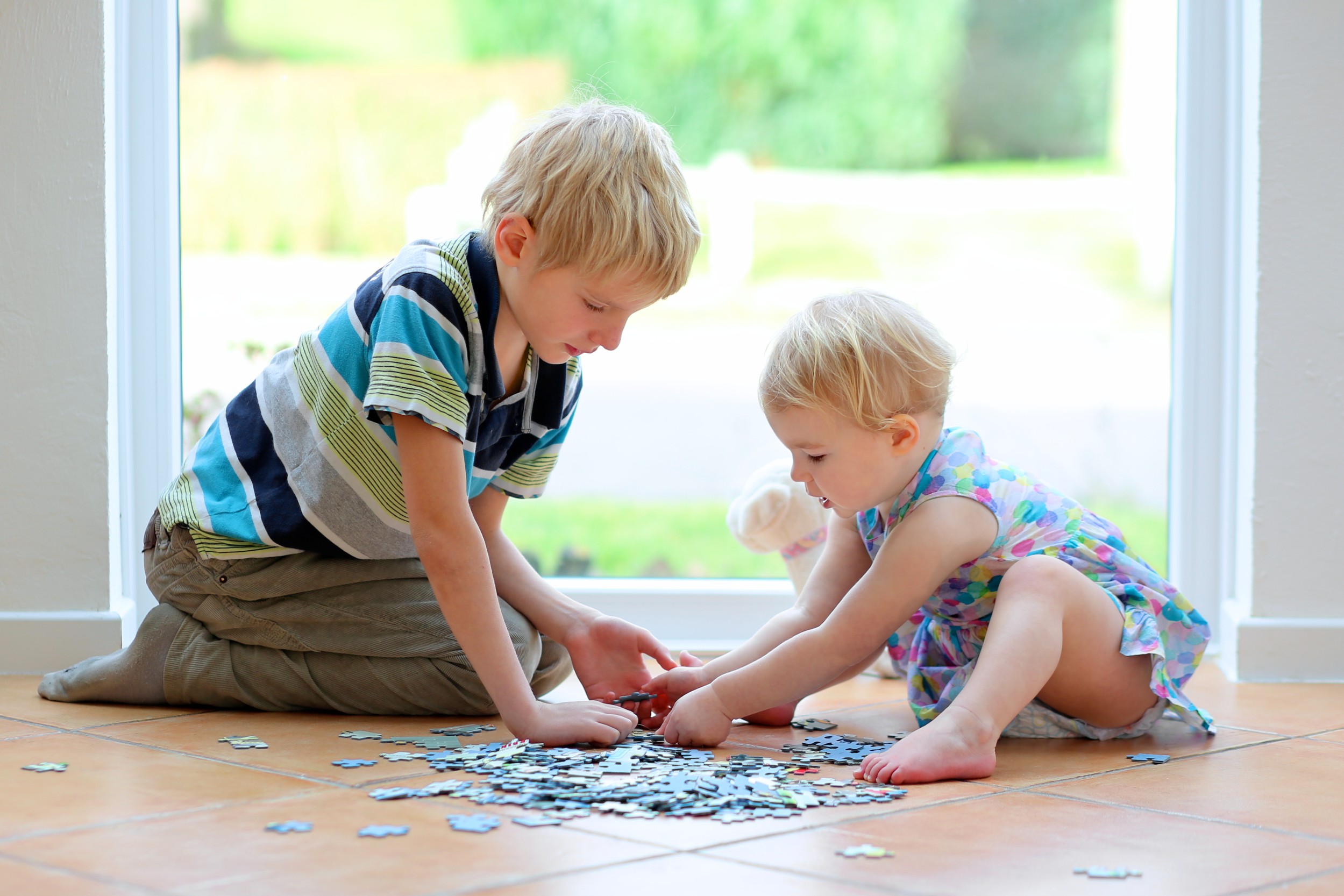 Two boys using a jigsaw puzzle on a floor