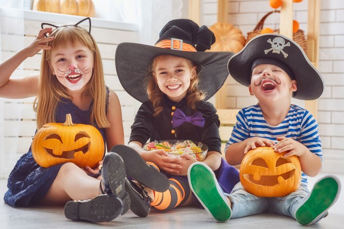three kids laughing and wearing costumes