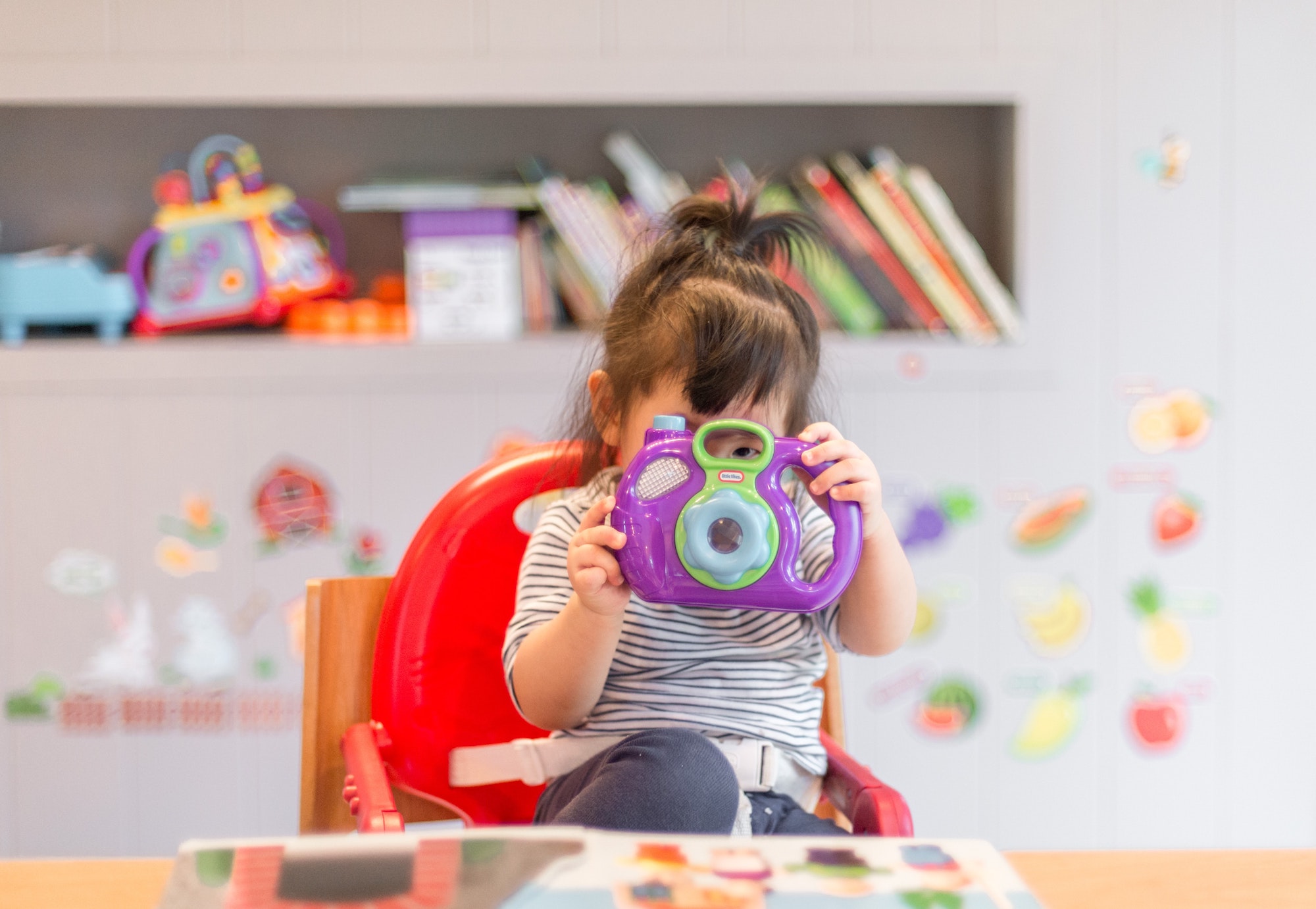 little girl at daycare playing with a toy camera