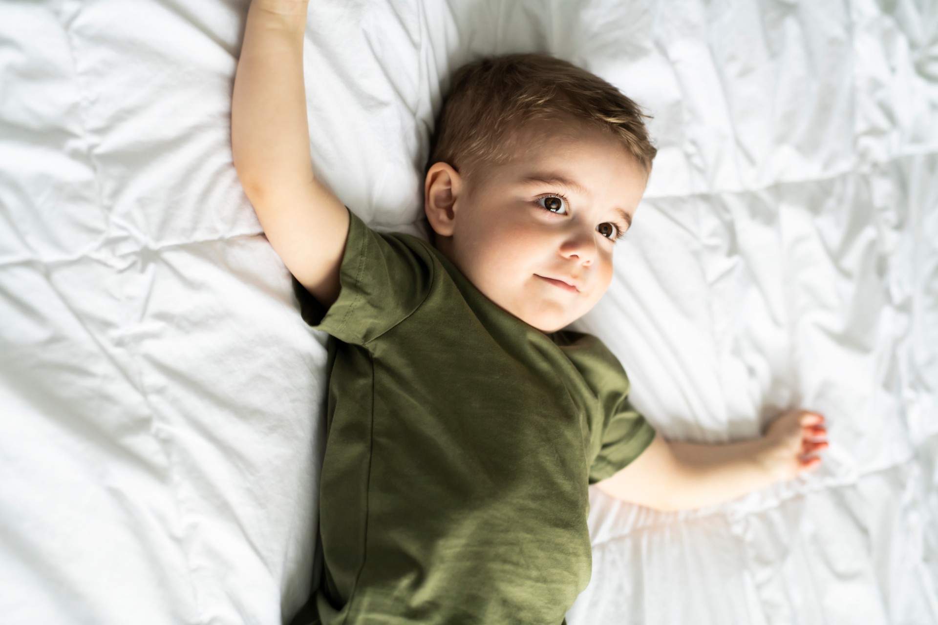 Toddler boy lies awake in bed
