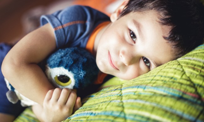 Young boy lying in bed with Teddy bear