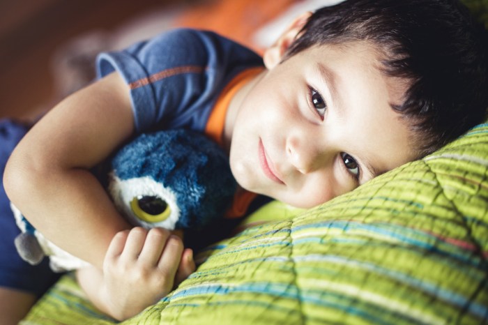 Young boy lying in bed with Teddy bear