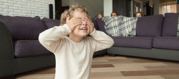 Child and parents playing hide-and-seek in their living room