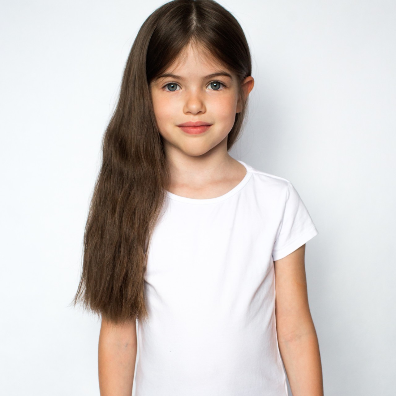 Young girl posing against a white wall