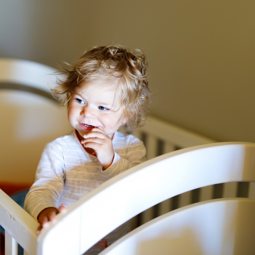 Toddler girl standing in her crib
