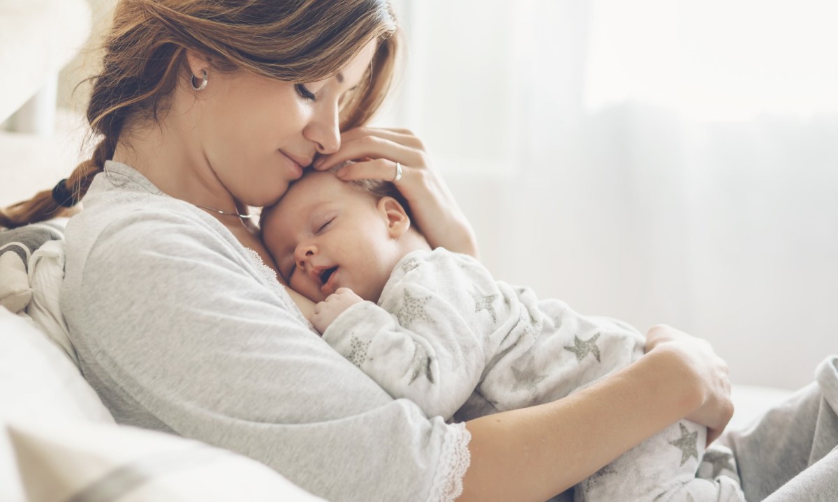 Mother holding her baby in bed