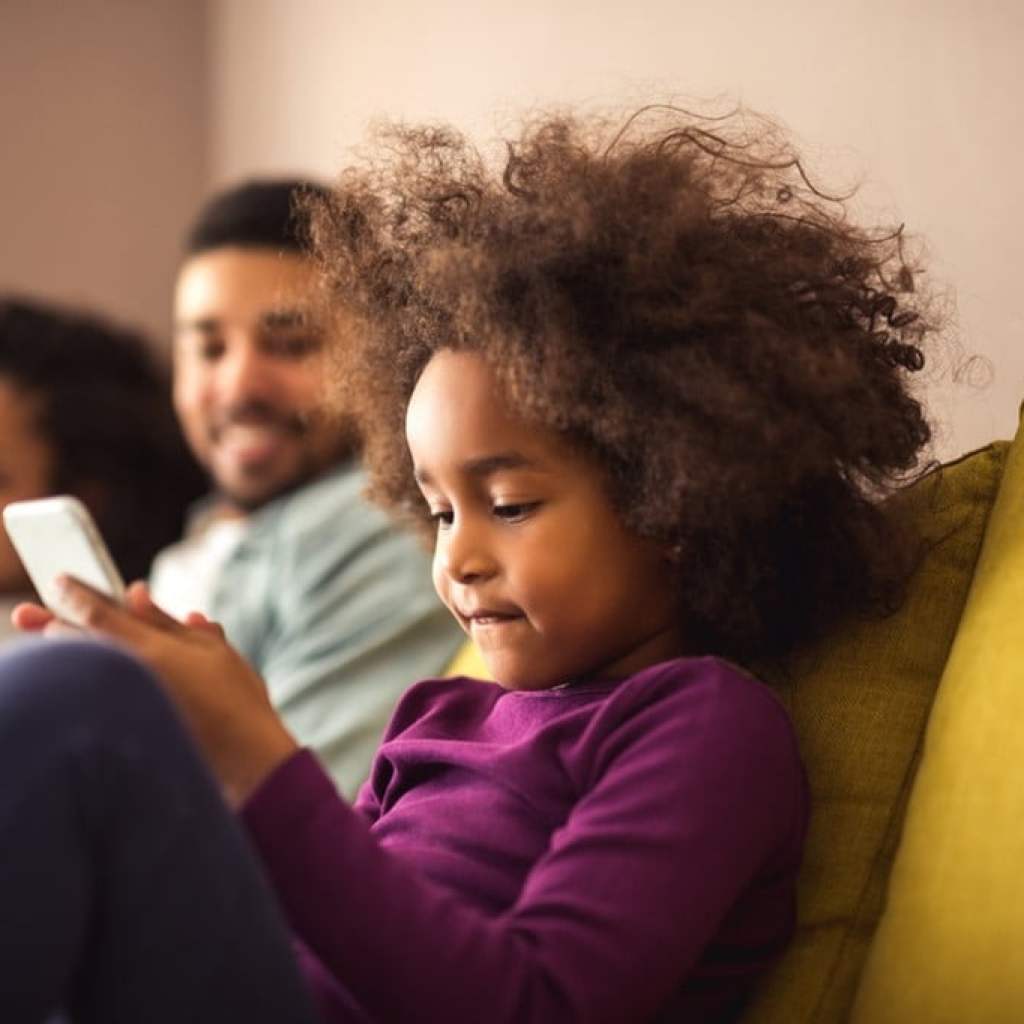 A child on a cellphone while their parents sit next to them.
