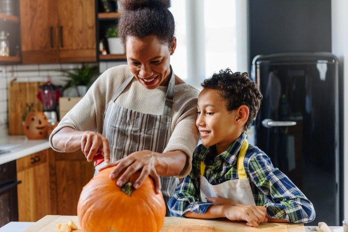 A mother and son carve a Halloween pumpkin