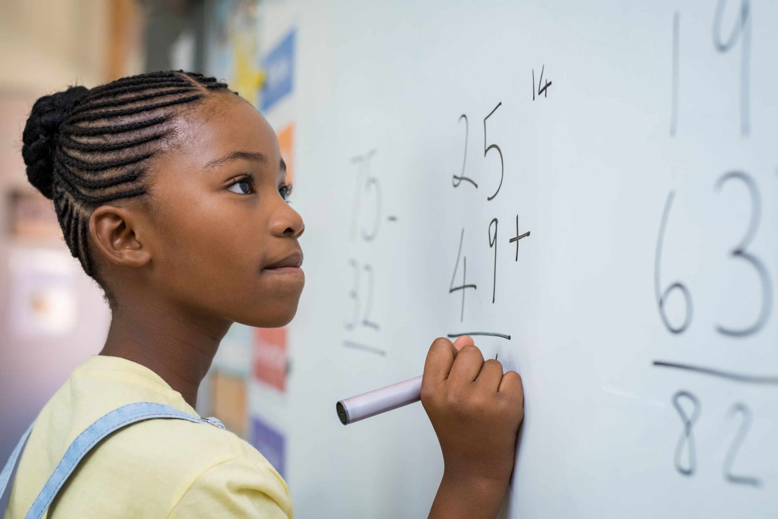 Student solving math problem on a white board