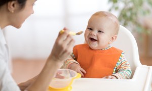 Mom spoon-feeding baby food,