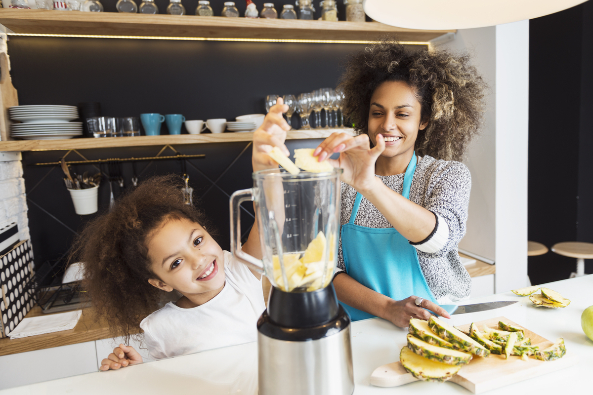 A mother and daughter have fun with a blender.