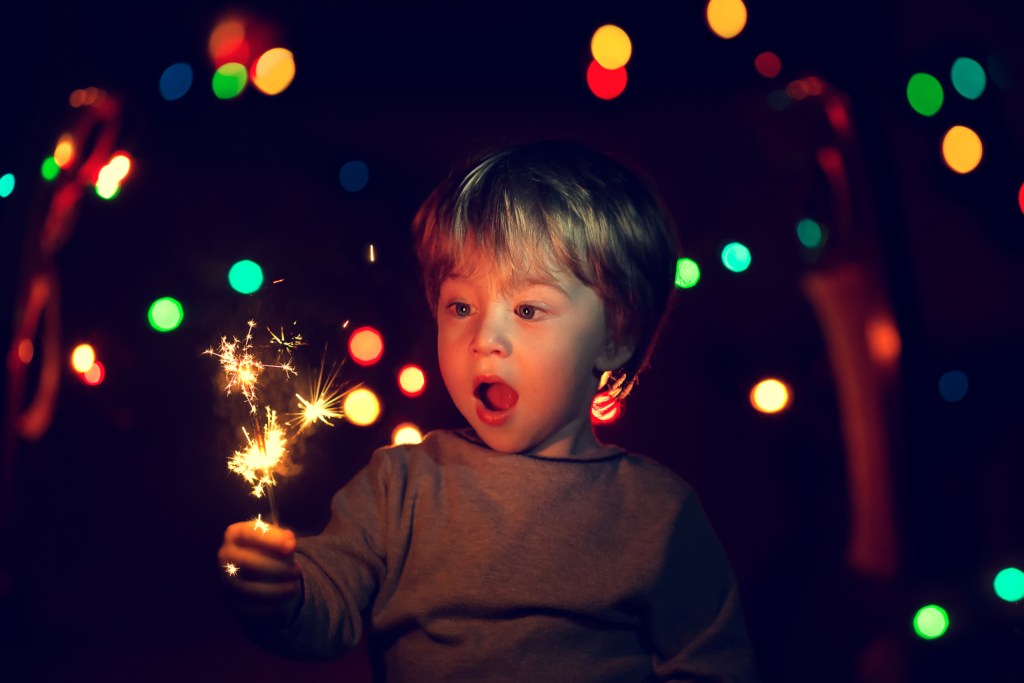 Toddler boy holding a sparkler at a party
