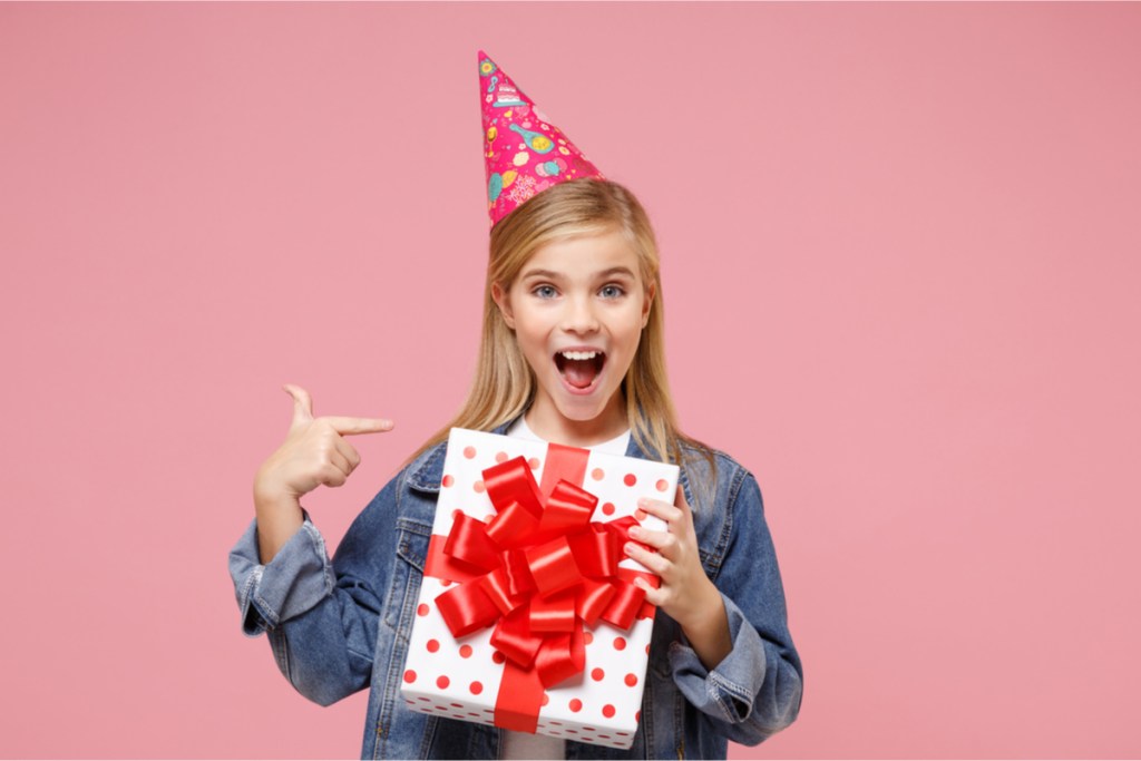 Pre-teen girl smiling, holding birthday present