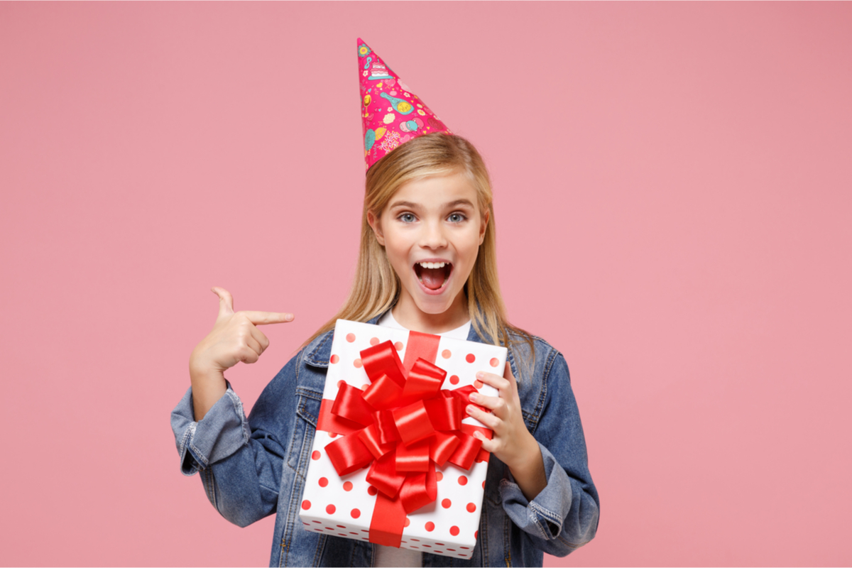 Pre-teen girl smiling, holding birthday present