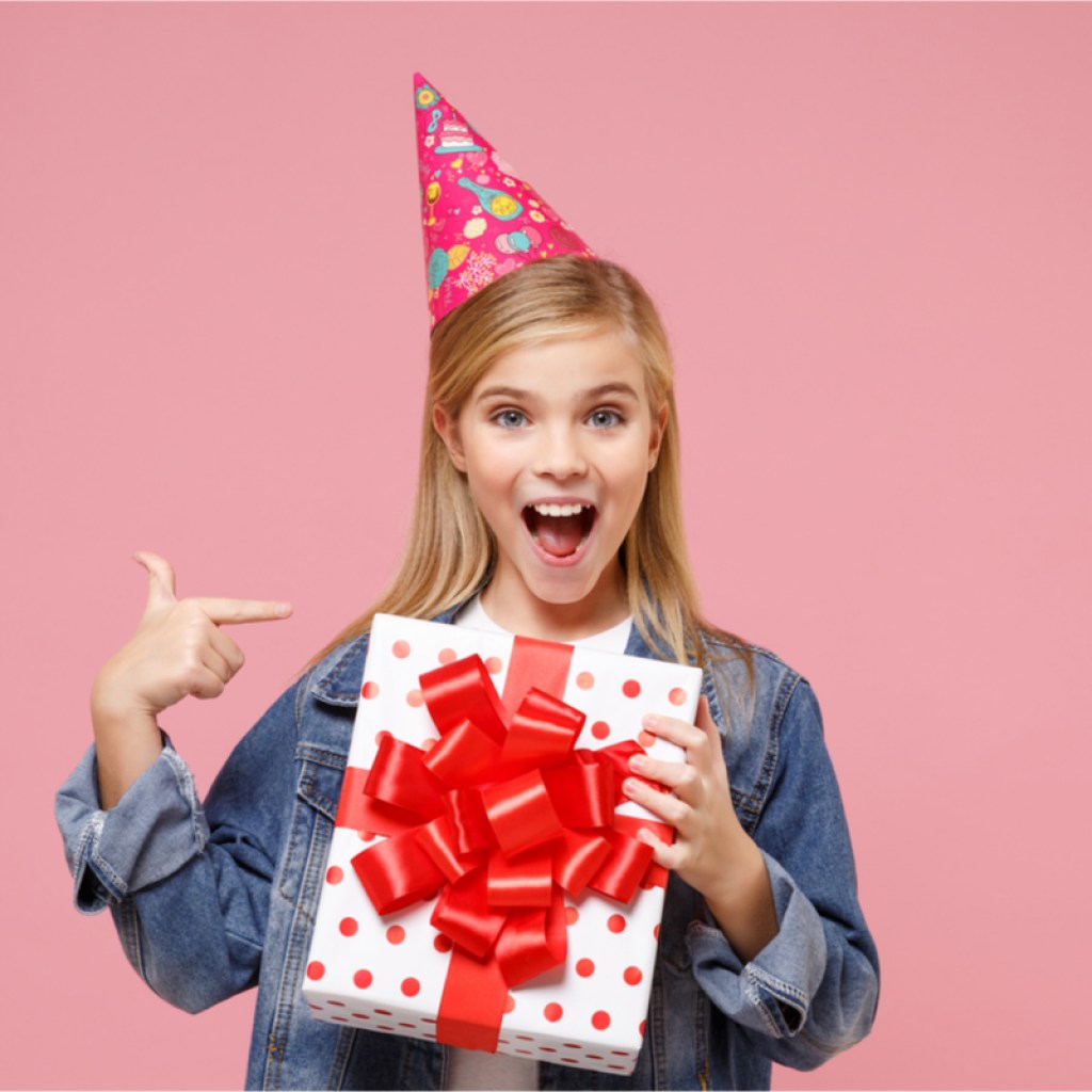 Pre-teen girl smiling, holding birthday present