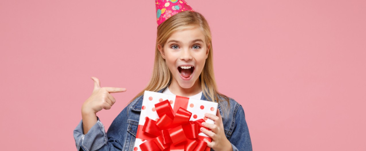 Pre-teen girl smiling, holding birthday present