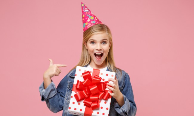 Pre-teen girl smiling, holding birthday present.
