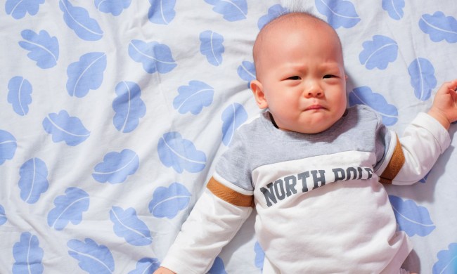 Baby boy upset while lying on a blanket