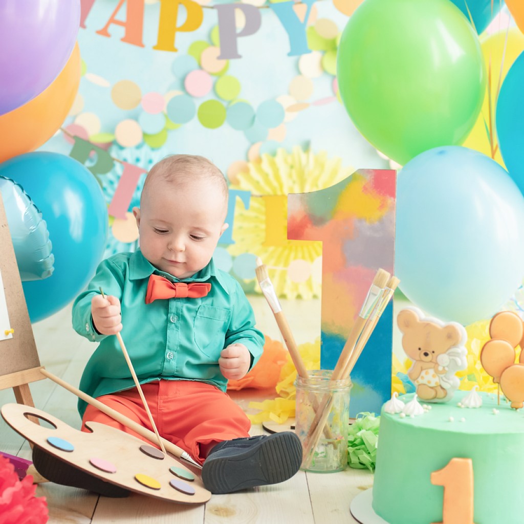 Baby painting with balloons and cake for first birthday