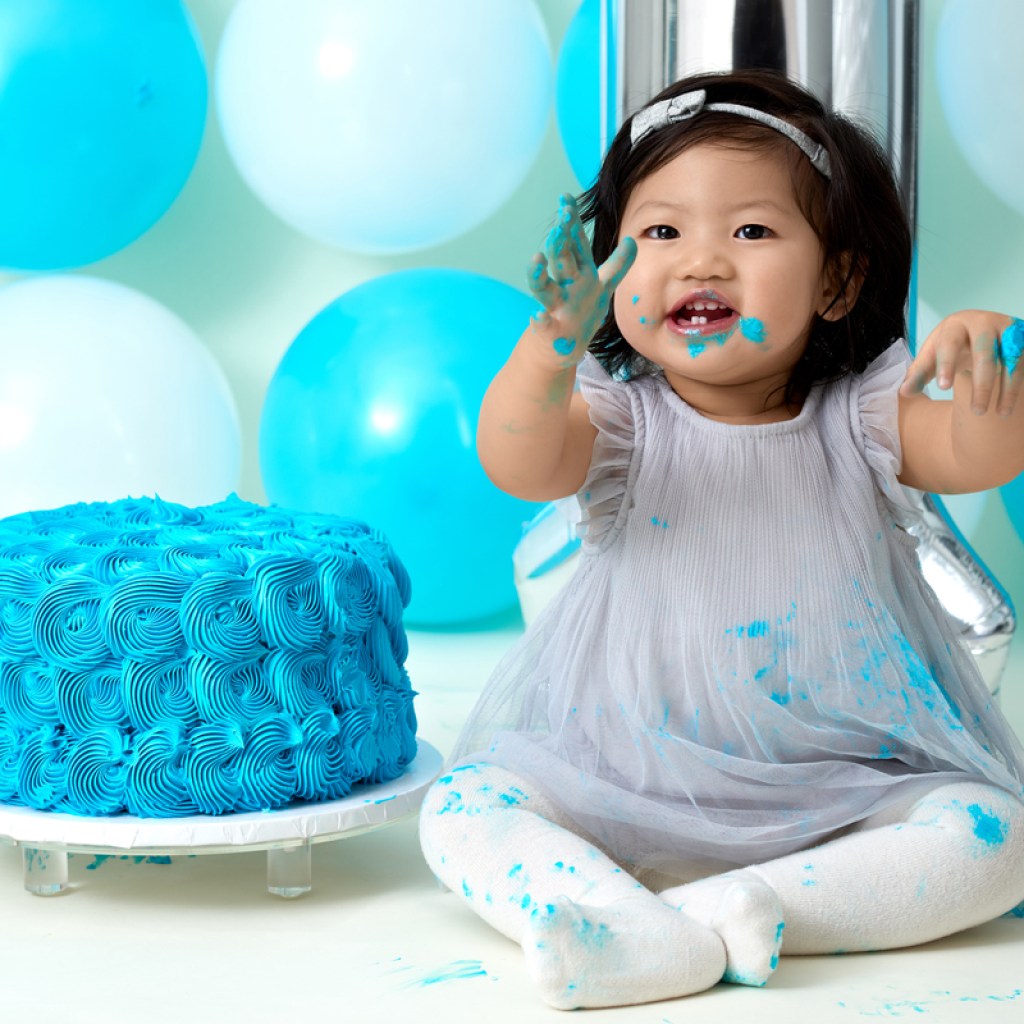 Baby girl is all smiles with her blue first birthday cake