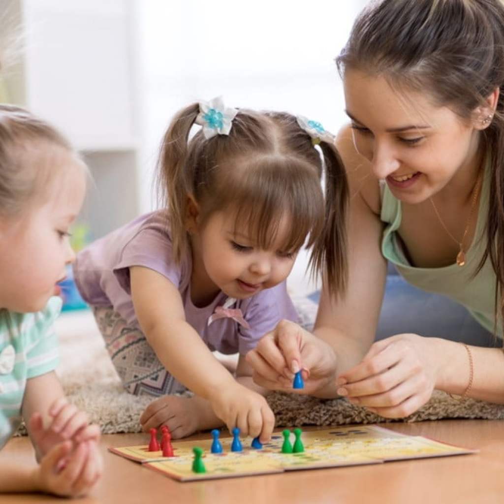 Woman and toddlers playing board game