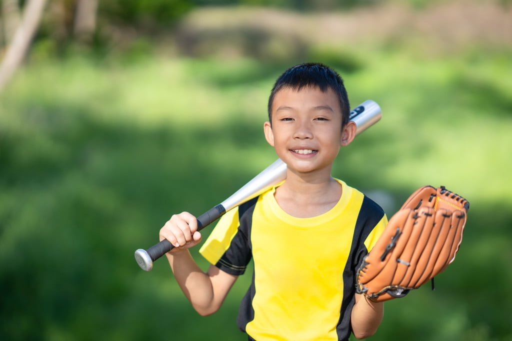 Smiling boy going to a sports party with bat and glove