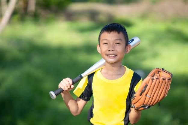 Smiling boy going to a sports party with bat and glove