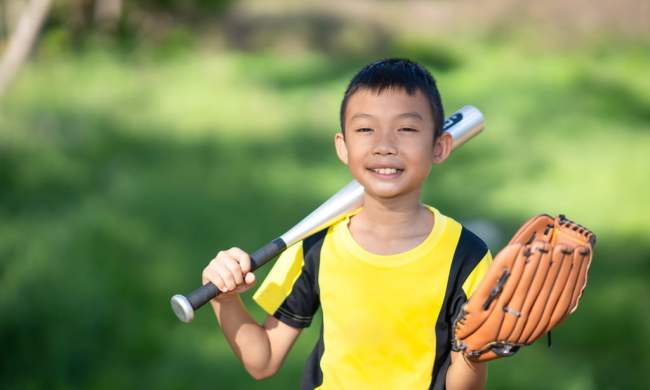 Smiling boy going to a sports party with bat and glove
