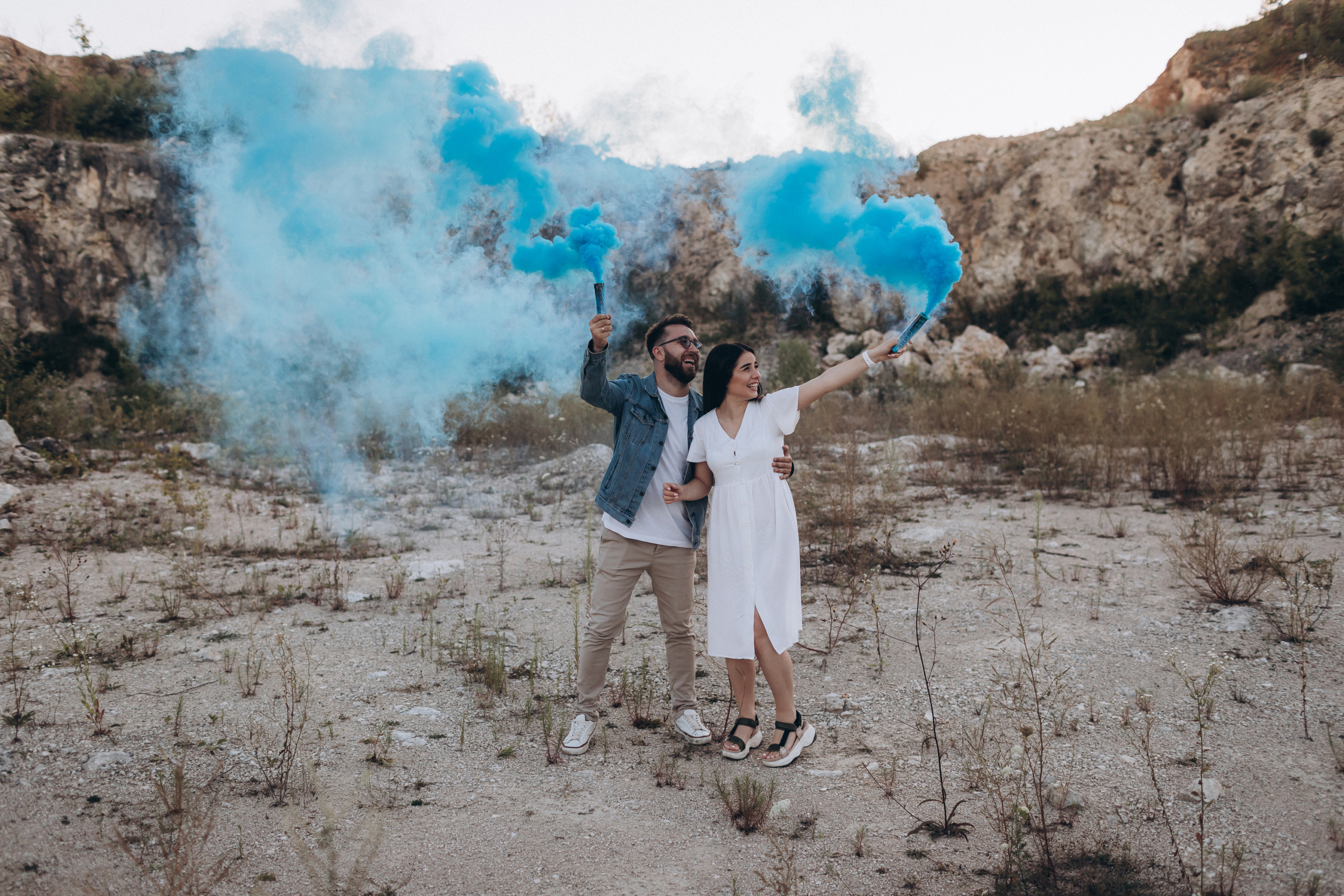 Pregnant couple holding blue smoke cannons celebrating