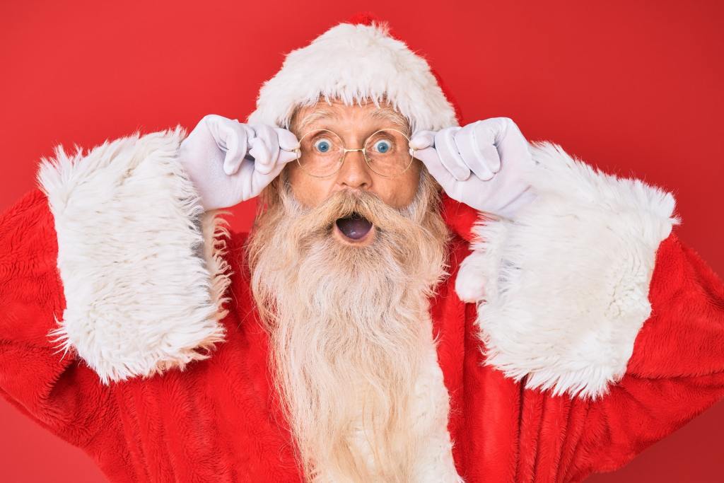 A surprised Santa against a red wall.