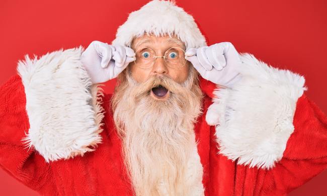 A surprised Santa against a red wall