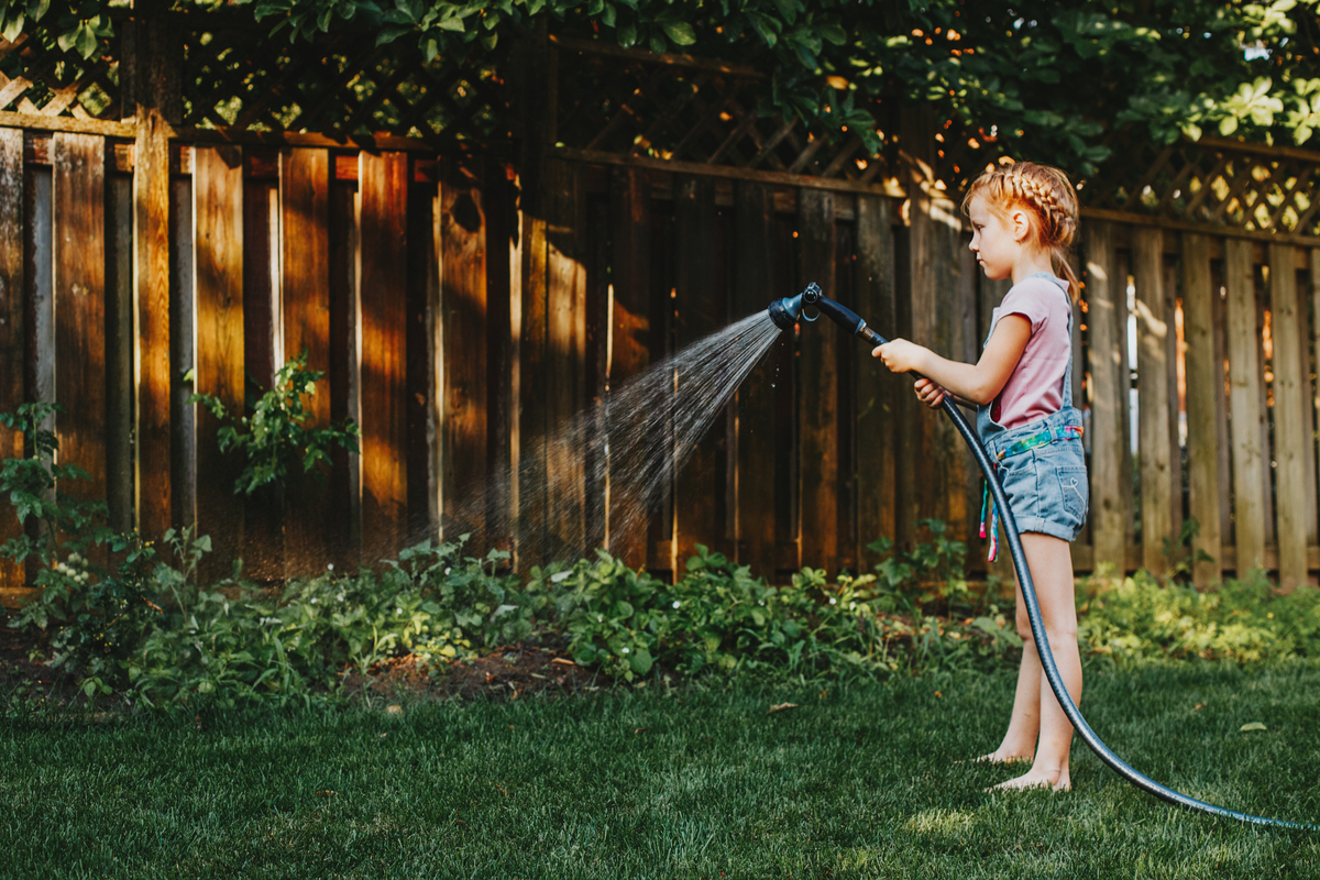 A girl waters the lawn